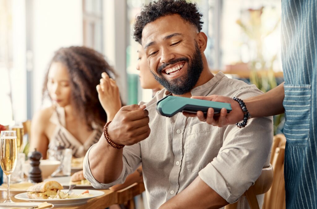 Future of payments technology concept. Smiling man paying contactless with payment card.